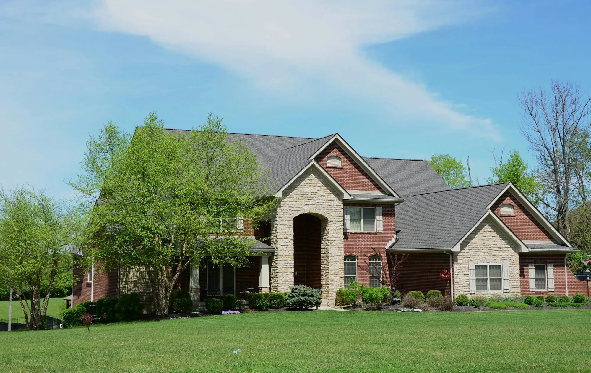 Two-story brick and stone house with a large arched entry