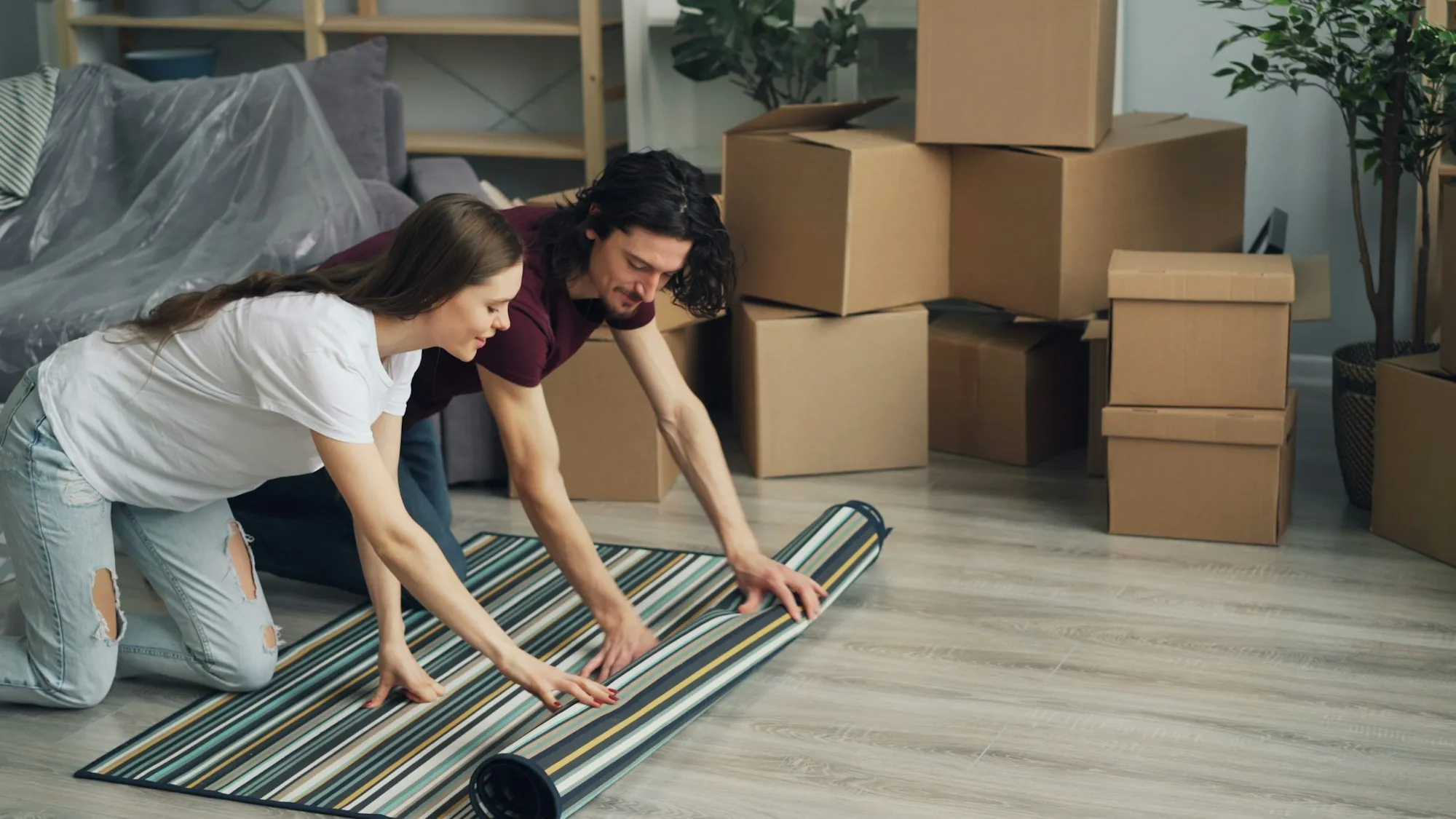 Couple unrolling a striped rug among moving boxes